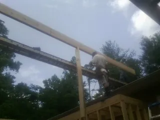Carpenter setting a ridge beam over a new addition frame — Ice Dam Removal by Roofing Brothers in Simpsonville