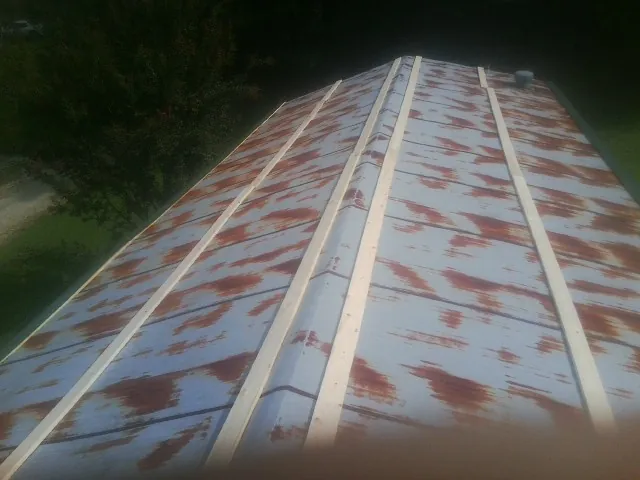 Rusted metal roof panels with new wood purlins before replacement — Storm Damage Roof Repair in Simpsonville by Roofing Brothers
