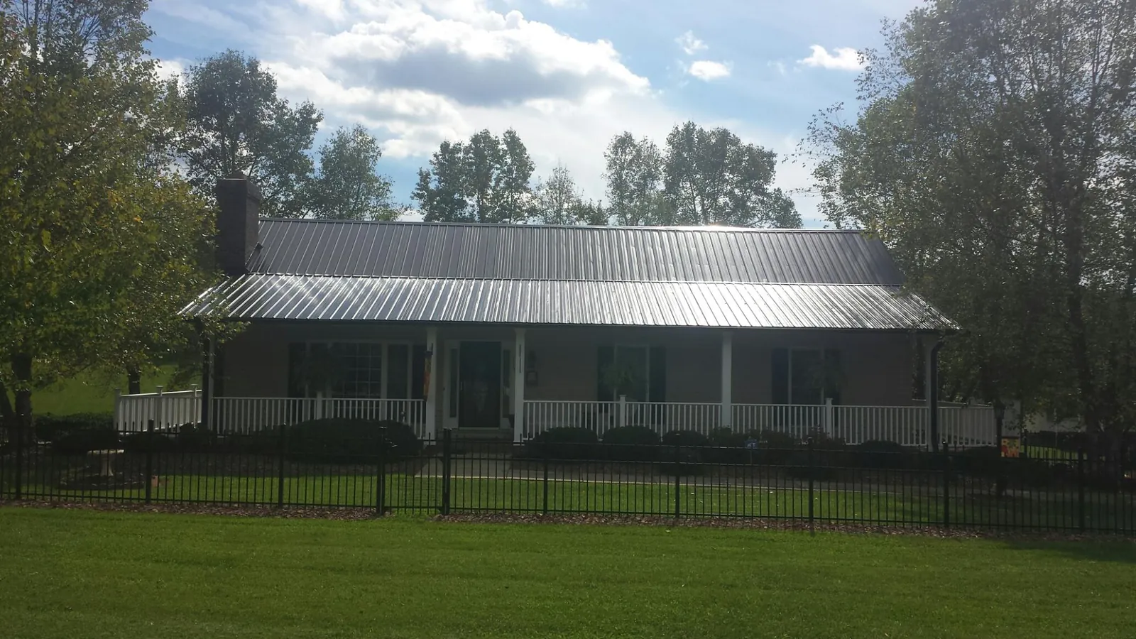 Gray metal roof on a brick ranch with a full width front porch — Gutter Guard Installation work by our crew in Simpsonville