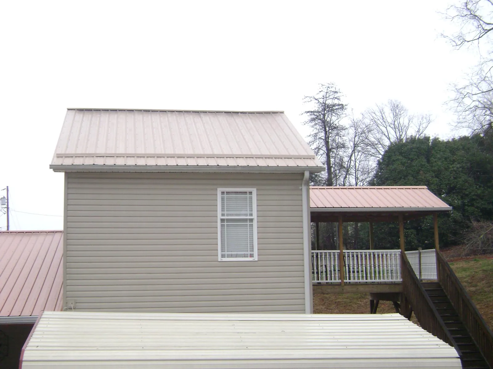 Tan metal roofs on a two story addition and attached porch, from a Roof Replacement job in Simpsonville