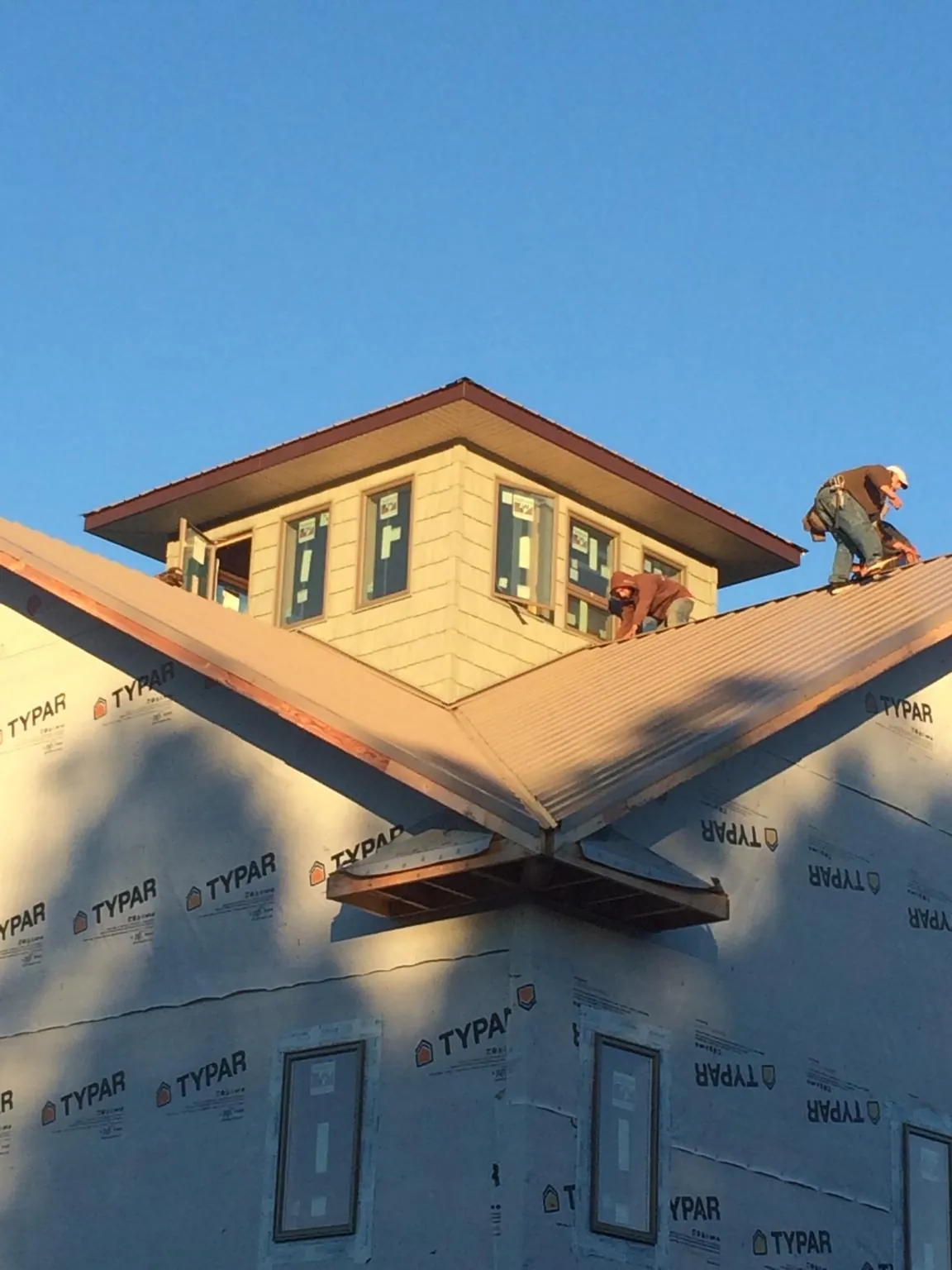 Roofers working around a rooftop cupola on a new metal roof at sunset — Roof Waterproofing in Simpsonville by Roofing Brothers